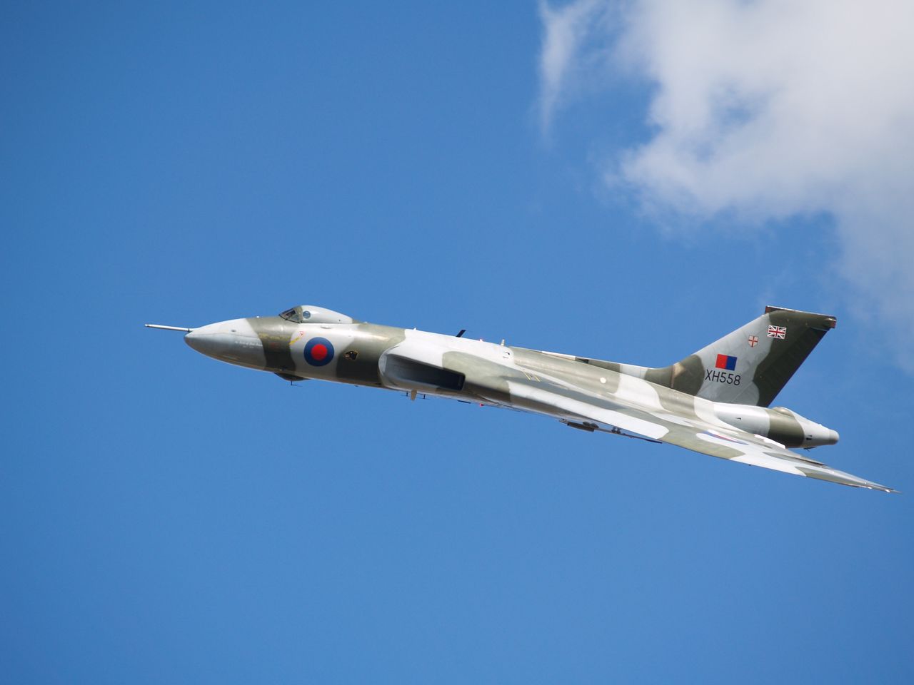 A military aircraft in flight against a bright blue sky, showcasing aviation excellence.