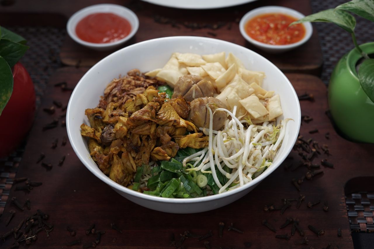 Delicious bowl of traditional Indonesian mie ayam served with fresh ingredients and spicy sauces.